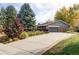 Home exterior with a wide driveway, a two-car garage, mature trees, and manicured landscaping at 1800 S Niagara Way, Denver, CO 80224