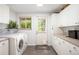A well-organized laundry room featuring white cabinets, gray tile floors, washer, and dryer at 1800 S Niagara Way, Denver, CO 80224