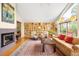 Inviting living room featuring a fireplace, large picture window, hardwood floors, and a wall of custom bookshelves at 1800 S Niagara Way, Denver, CO 80224