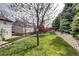 Spacious backyard with lush green grass, trees, and a retaining wall near a neighboring fence at 10554 Tracewood Cir, Highlands Ranch, CO 80130