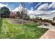 Well-maintained backyard with green grass, trees, retaining walls, and patio seating area at 10554 Tracewood Cir, Highlands Ranch, CO 80130