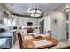 Well-lit kitchen featuring white cabinets, stainless steel appliances, and a stylish pendant light above wooden table at 10554 Tracewood Cir, Highlands Ranch, CO 80130