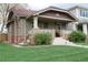 Inviting brick home featuring a tiled roof, a covered porch, and lush landscaping at 1395 S Josephine St, Denver, CO 80210