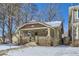 Charming brick home featuring a cozy front porch, snow covered yard, and mature trees at 1395 S Josephine St, Denver, CO 80210