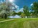 Scenic pond view with fountain, lush greenery, and walking path in a community setting at 50 E Highline Cir # 101, Centennial, CO 80122