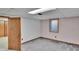 Unfinished basement offers potential with carpet flooring, a window, and a door to a storage space at 4960 S Fox St, Englewood, CO 80110