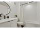 Modern bathroom featuring a sleek vanity, a round mirror, and a tiled shower with a patterned curtain at 2120 N Downing St # 209, Denver, CO 80205