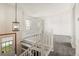 A neutral landing with white bannisters and trim, and a modern light fixture hanging above the staircase at 11182 W 103Rd Cir, Broomfield, CO 80021