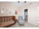 A well-lit Bedroom includes a crib, chair and ottoman, and closet for a calming space at 2754 W 69Th Ave, Denver, CO 80221