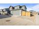 Exterior view of the gray home featuring a gray two-car garage, gravel landscaping, and wood fencing at 2754 W 69Th Ave, Denver, CO 80221