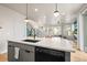 Modern kitchen island with white countertop, black sink, dishwasher, and pendant lighting, overlooking the staircase at 2754 W 69Th Ave, Denver, CO 80221