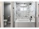 Bright bathroom showcasing a tub with textured marble-style tiling, a sleek shower head, and a toilet at 10305 W 34Th Pl, Wheat Ridge, CO 80033