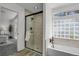 Modern bathroom with tiled shower, separate bathtub, and natural light from window at 1894 S Marshall Cir, Lakewood, CO 80232