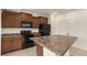 Bright kitchen featuring a center island, ample counter space, and sleek black appliances and wooden cabinetry at 19060 E 54Th Pl, Denver, CO 80249