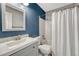 Stylish bathroom features a blue accent wall, white vanity and a shower-tub combo with a white shower curtain at 9662 Newcastle Dr, Highlands Ranch, CO 80130