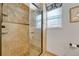 Luxurious shower with travertine tile, glass door, built-in seat, and a rainfall shower head at 9662 Newcastle Dr, Highlands Ranch, CO 80130