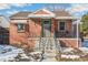 Brick ranch home with a covered porch and steps, situated on a snow-dusted lot at 2895 Dexter St, Denver, CO 80207