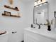 Bright bathroom featuring a modern vanity, decorative shelves, and a sleek mirror with contemporary lighting at 1517 S Elkhart St, Aurora, CO 80012