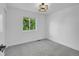 Empty bedroom with gray carpet and a window view of lush green trees, illuminated by a modern light fixture at 1517 S Elkhart St, Aurora, CO 80012