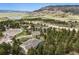 Stunning aerial view of a home nestled among mature trees with views of rolling hills, a lake, and mountains at 20413 Bald Mountain Ct, Monument, CO 80132