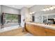 Bathroom with a soaking tub, shuttered window, and wood vanity with double sinks at 20413 Bald Mountain Ct, Monument, CO 80132