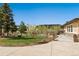 Beautifully landscaped front yard featuring a paved driveway and walkway, mature trees, and mountain views at 20413 Bald Mountain Ct, Monument, CO 80132