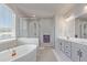 Bright bathroom featuring a soaking tub, walk-in shower, and gray cabinetry at 434 W 128Th Dr, Westminster, CO 80234