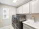 Well-lit laundry room with gray washer/dryer, utility sink, and plenty of cabinet storage at 1101 E Witherspoon Dr, Elizabeth, CO 80107