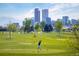 Scenic golf course with lush green fairways, mature trees, and a stunning city skyline backdrop at 1652 N Lafayette St # 1, Denver, CO 80218