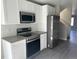 Kitchen featuring stainless steel appliances, white cabinets, and gray countertops, next to a staircase at 1652 N Lafayette St # 1, Denver, CO 80218