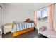 Bright bedroom with wood floors, light pink curtains and a bed with under-bed storage at 10463 Adams St, Northglenn, CO 80233