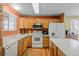 Functional kitchen with wood cabinets, white appliances, and an island at 10463 Adams St, Northglenn, CO 80233
