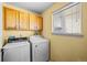 Laundry room with washer, dryer, cabinets, and window with blinds at 10463 Adams St, Northglenn, CO 80233
