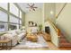 Bright living room with a vaulted ceiling, large windows, and hardwood floors leading to an adjacent staircase at 10463 Adams St, Northglenn, CO 80233