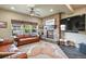 Comfortable living room with a stone fireplace, large windows for natural light, and ceiling fan at 12380 Jasper Pointe Way, Castle Pines, CO 80108