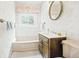 Bathroom with vintage patterned wallpaper, window, and vanity with a round mirror at 1930 Taft Dr, Lakewood, CO 80215