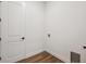 Neutral laundry room with white walls, wood-look flooring, and a closed white door at 1111 Joseph Pl, Erie, CO 80026