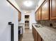 Long galley kitchen with granite countertops and wood cabinets at 7455 E Quincy Ave # 101, Denver, CO 80237