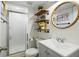 Stylish bathroom showcasing industrial-style shelving, a round mirror, and a toilet next to a glass-enclosed shower at 9521 Joyce Ln, Highlands Ranch, CO 80126