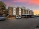 Four story apartment building with tan and white facade, parking, and sunset sky at 384 S Ironton St # 408, Aurora, CO 80012
