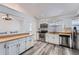 Well-lit kitchen featuring stainless steel appliances, white cabinetry, and wood-look floors at 18347 E Nassau Dr, Aurora, CO 80013