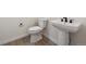 Compact half bath featuring a modern pedestal sink and a matching toilet, complete with sleek fixtures at 5537 Riverbend Ave, Firestone, CO 80504