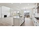 This kitchen features white cabinets, a kitchen island, and stainless appliances, with a living room fireplace view at 5537 Riverbend Ave, Firestone, CO 80504