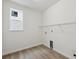 Compact laundry room with wood-look floors, a utility sink hookup, and a single window at 5537 Riverbend Ave, Firestone, CO 80504
