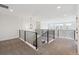 Open upstairs loft space with modern railings, plush carpeting, and ample natural light at 5537 Riverbend Ave, Firestone, CO 80504
