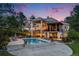 An expansive backyard featuring a pool, fire pit, string lights, stone accents, and elegant two-story home at dusk at 10914 Remmick Ridge Rd, Parker, CO 80134