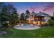 Beautiful backyard with a pool, outdoor fire pit, expansive lawn, and a large home at dusk at 10914 Remmick Ridge Rd, Parker, CO 80134