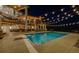 Stunning outdoor pool area with a diving board, beautiful lighting, and backyard entertainment space at night at 10914 Remmick Ridge Rd, Parker, CO 80134