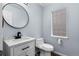 This powder room offers a stylish round mirror, a vanity and a window at 1963 Hogan Ct, Castle Rock, CO 80109