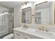 Bright bathroom featuring a double vanity, sleek gold fixtures, and a glass-enclosed shower at 12164 E Amherst Cir, Aurora, CO 80014